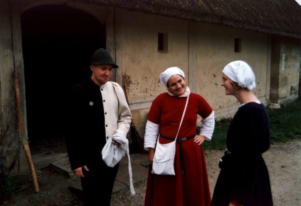 Group of people dressed in medieval clothes in front of a clay/thatch house
